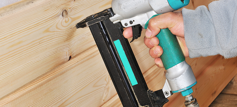 A pneumatic nailer is used to install 2 by 6 wood panelling