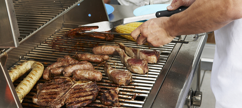 A man grills a variety of meats on a grill.