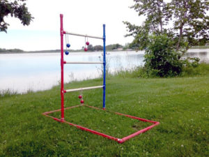 Fully assembled ladder golf game sits near a lake waiting for someone to enjoy a game.
