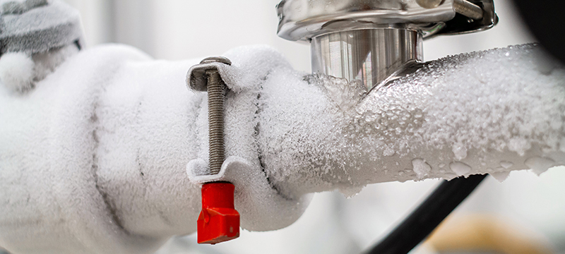 An outdoor pipe is covered with ice.