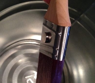 magnet holding a paint brush onto the side of a metal bucket to dry