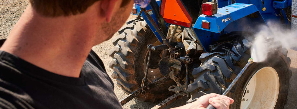 Using a commercial-grade pressure washer to clean farm equipment