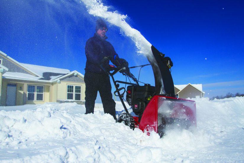 Person using a gas snowblower to clear a path to their street