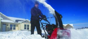 Person using a gas snowblower to clear a path to their street