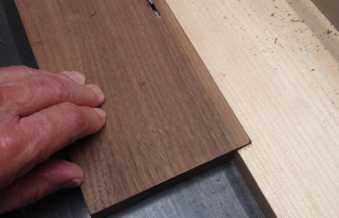 Use a sacrificial piece with a notch to assist in thin rips on your table saw