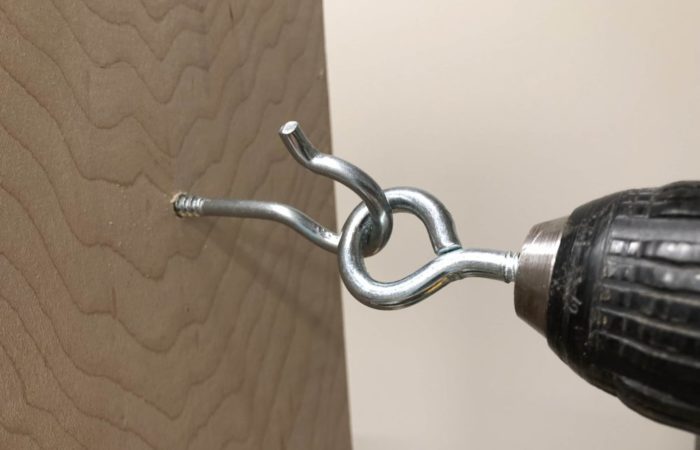 Chuck an eye bolt into your drill to assist in screwing in a screw hook. The eye bolt will grab the hook and turn it in without much effort.