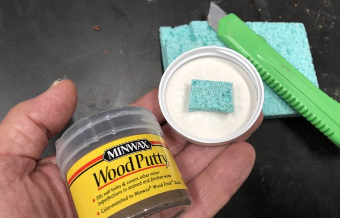 Add a small piece of moist sponge to the top of your wood putty lid to keep it from drying out