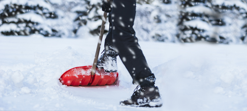 Feature Image showing a person shoveling snow with a red plastic shovel.