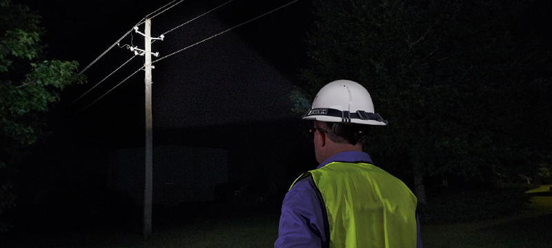 Professional using an Intrinsically Safe Headlamp on a darkened worksite.