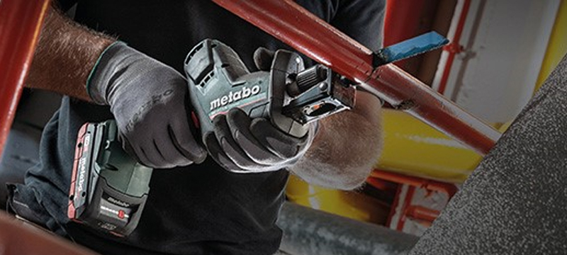 Professional using a Metabo Reciprocating Saw to cut through a pipe.