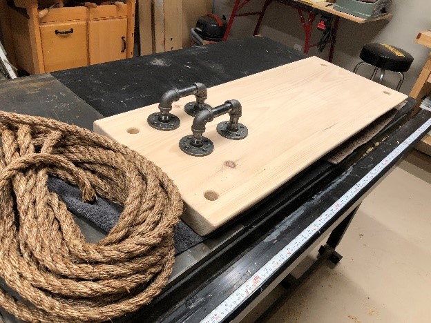 A wood board, pipe fittings, and a rope in a work shop