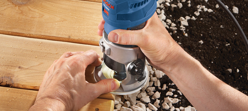 A homeowner uses Bosch Colt Variable-Speed Palm Router on the edges of their deck.