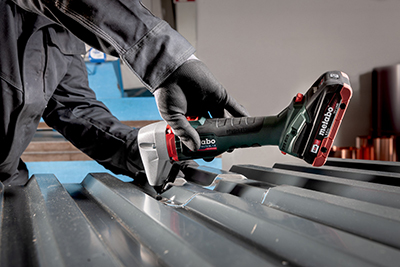 A metalworker works on a piece of sheet of metal using the Metabo 18 Volt Cordless Nibbler.