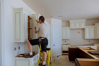 Man installing kitchen cabinets during a kitchen model.