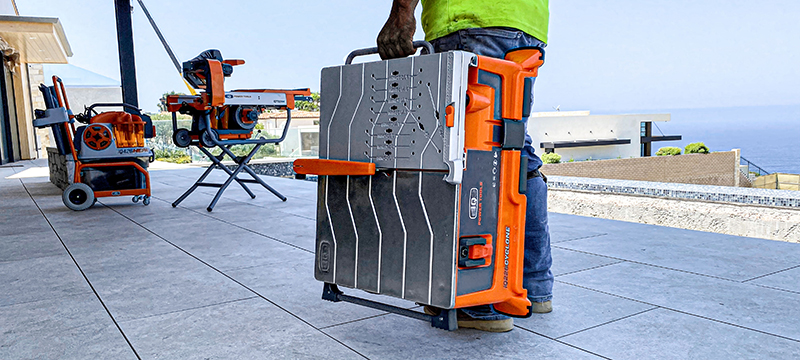 A worker carries iQ Power Tools' new dry-cut table saw on the jobsite.