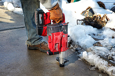 A worker uses the Milwaukee M12 HAMMERVAC Universal Dust Extractor.