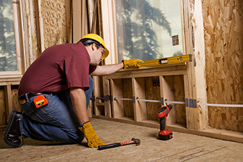 A carpenter uses a level on a window.