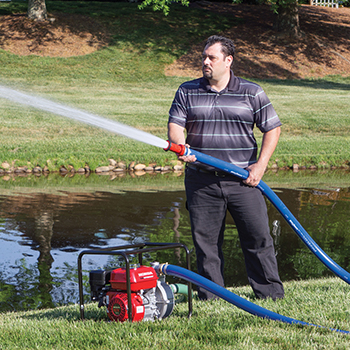 A man uses a Honda 2 Inch Water Pump to Water his lawn.