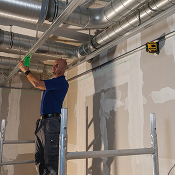 A workers uses the Stabila LAX 300 Green Laser Level Tool Set to level a suspension system.