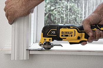 A DEWALT oscillating multi-tool is used to cut some trim around a window.