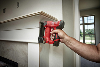 A Milwaukee M12 23-Gauge Cordless Pin Nailer is used to attached trim to a mantle.