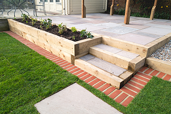 A raised garden bed is built into the side of a patio.