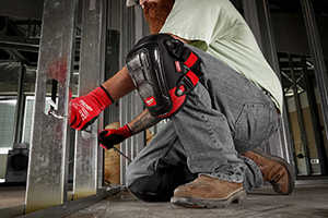 A worker wearing Milwaukee Performance Knee Pads installs electrical wire in a wall stud.