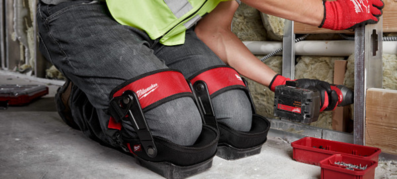 A worker installs a metal stud while wearing Milwaukee Performance Stabilizer Knee Pads.