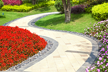 A decorative paver walkway winds through a backyard.