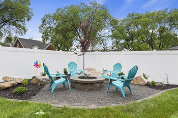 A fire pit sitting area is tucked into the corner of a backyard.