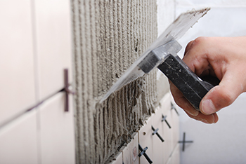 Mortar is applied to a wall using a notched trowel.