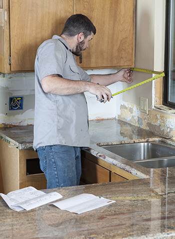 The wall of the backsplash is measured to determine square footage.