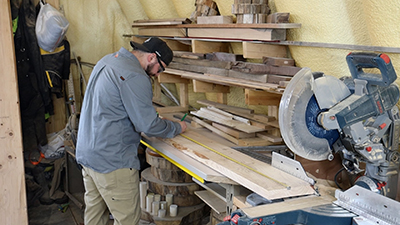 A 2x10-inch board is measured before being cut in half.