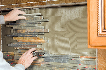 A mosaic tile sheet is applied to a backsplash.