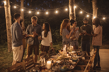 Friends celebrate in their backyard under illuminated string lights.