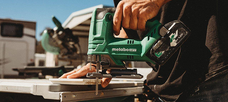 A worker uses the Metabo HPT MultiVolt Jig Saw to cut a piece of baseboard.