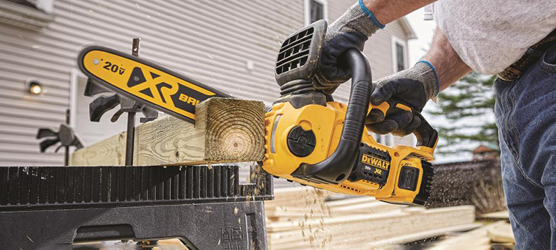 A DEWALT Compact Cordless Chainsaw is used to cut through a 4 by 4 piece of wood.