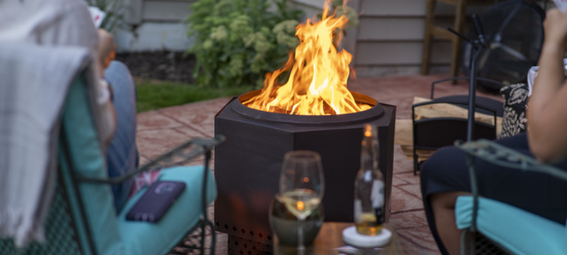 Two people sit around the Dragonfire Smokeless Fire Pit.