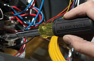 A Klein Tools 11-in-1 Magnetic Screwdriver is used to tighten a screw.