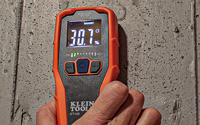 Moisture in a wall is read with a Klein Tools Pinless Moisture Meter.
