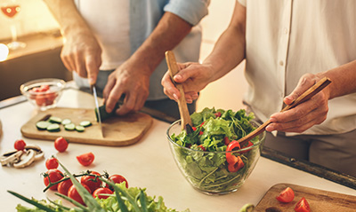 A couple prepares a salad.