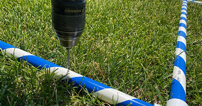 A cordless drill is used to drill holes in the PVC pipe.