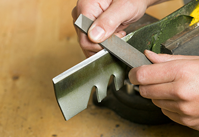 A file is used to sharpen a lawnmower blade.