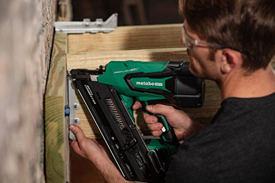 A construction worker attaches a joist to a deck frame with the Metabo HPT 36V Cordless Metal Connector Nailer.