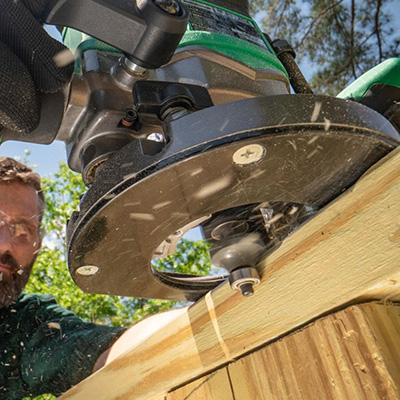 An underside view of the Metabo HPT 36V Cordless Plunge Router used to route a deck railing.