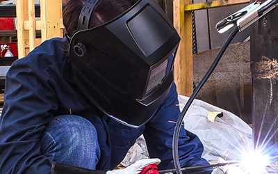 A welder wears a Forney Industries Easy Weld ADF Welding Helmet during work.