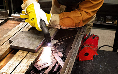A Forney Industries Easy Weld 20 P Plasma Cutter is used to separate a piece of metal.