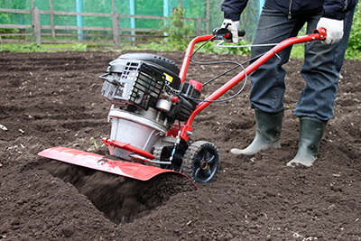 A rototiller is used to loosen soil in a garden.