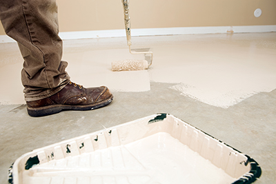 A paint roller is used to apply epoxy to a garage floor.