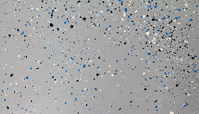 An epoxy floor with blue, black, and cream color flakes.